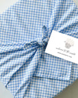 Baby boy gift box wrapped in blue gingham Furoshiki cotton fabric with welcome to the world lamb card