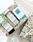kadoo calm spa curated gift box wrapped in reusable furoshiki fabric wrap. gifts included lavender bath salt, olive flower soy candle, tea tree peppermint soap, jasmine tea and more