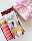 kadoo desk essential for her gift box. Gift items: christian lacroix notebook, pink que water bottle, cookie and more. wrapped in pink furoshiki fabric.