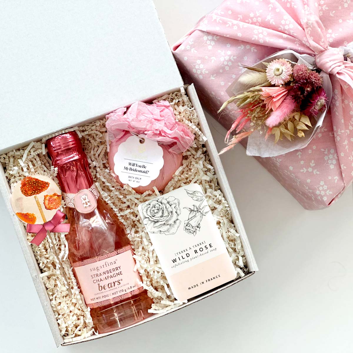 kadoo bridesmaid furoshiki gift box for your wedding party. will you be my bridesmaid bath balm, sugarfina champagne bear, lollipop, & bar soap.