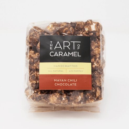 A clear plastic bag of 'The Art of Caramel' handcrafted caramel popcorn in the 'Mayan Chili Chocolate' flavor, shown against a plain white background.