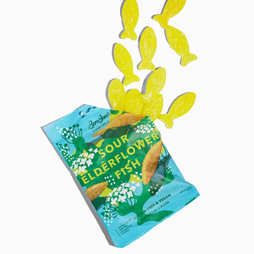 A package of opened BonBon Sour Elderflower Fish gummy candies, with several yellow fish-shaped gummies coming out of the bag on a plain white background.