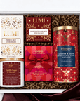 A curated gift box set containing multiple brands: Lumi White Hot Chocolate, Lumi Handcrafted Caramels, Goodio Craft Chocolate, and Whittard Biscuits, arranged in a white box with brown crinkle paper filler.