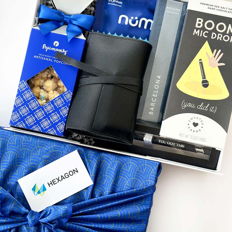 Gift basket with popcorn, notebook,  chocolate, and a card with HEXAGON branding.