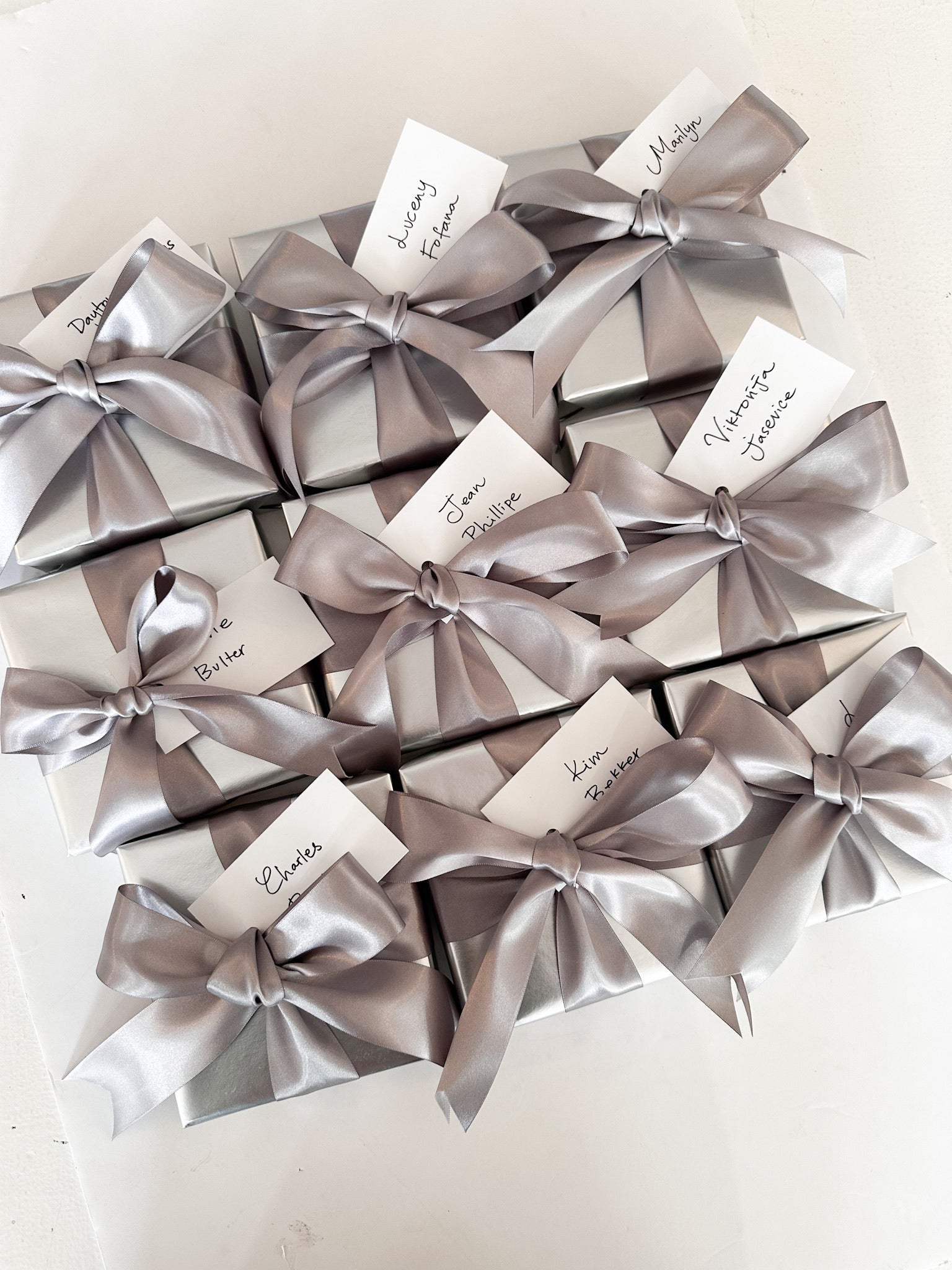 Silver gift boxes with ribbons and name tags on a white background