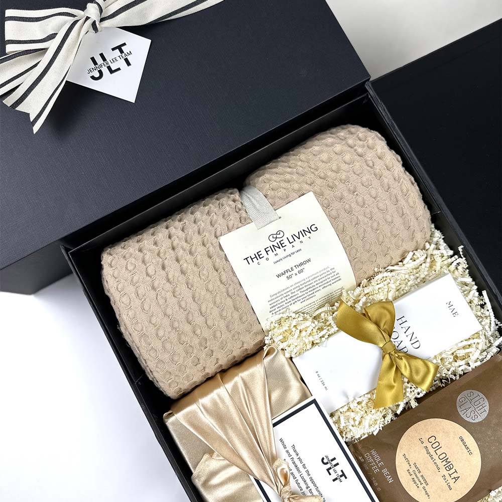 Gift set with textured blanket, decorative bow, and branded packaging on a white background