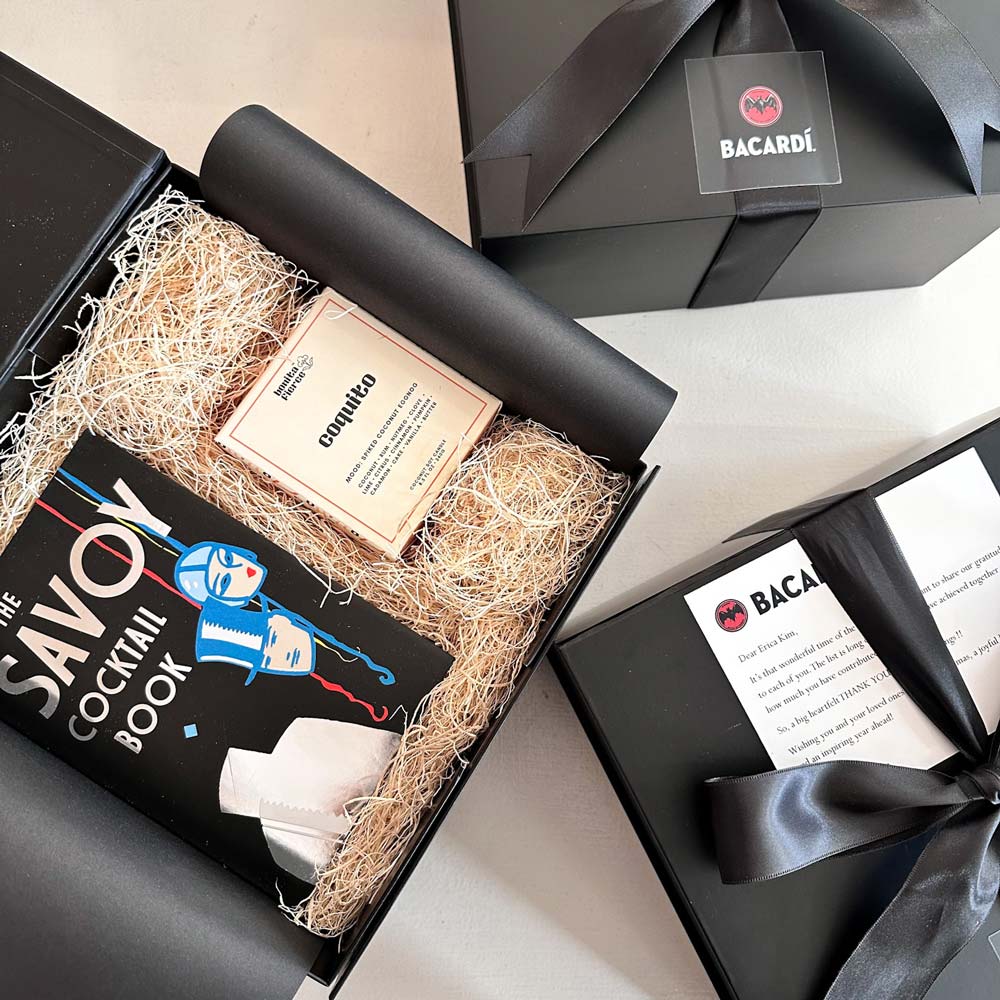 Gift set with 'The Savoy Cocktail Book' and Bacardi items on a light background