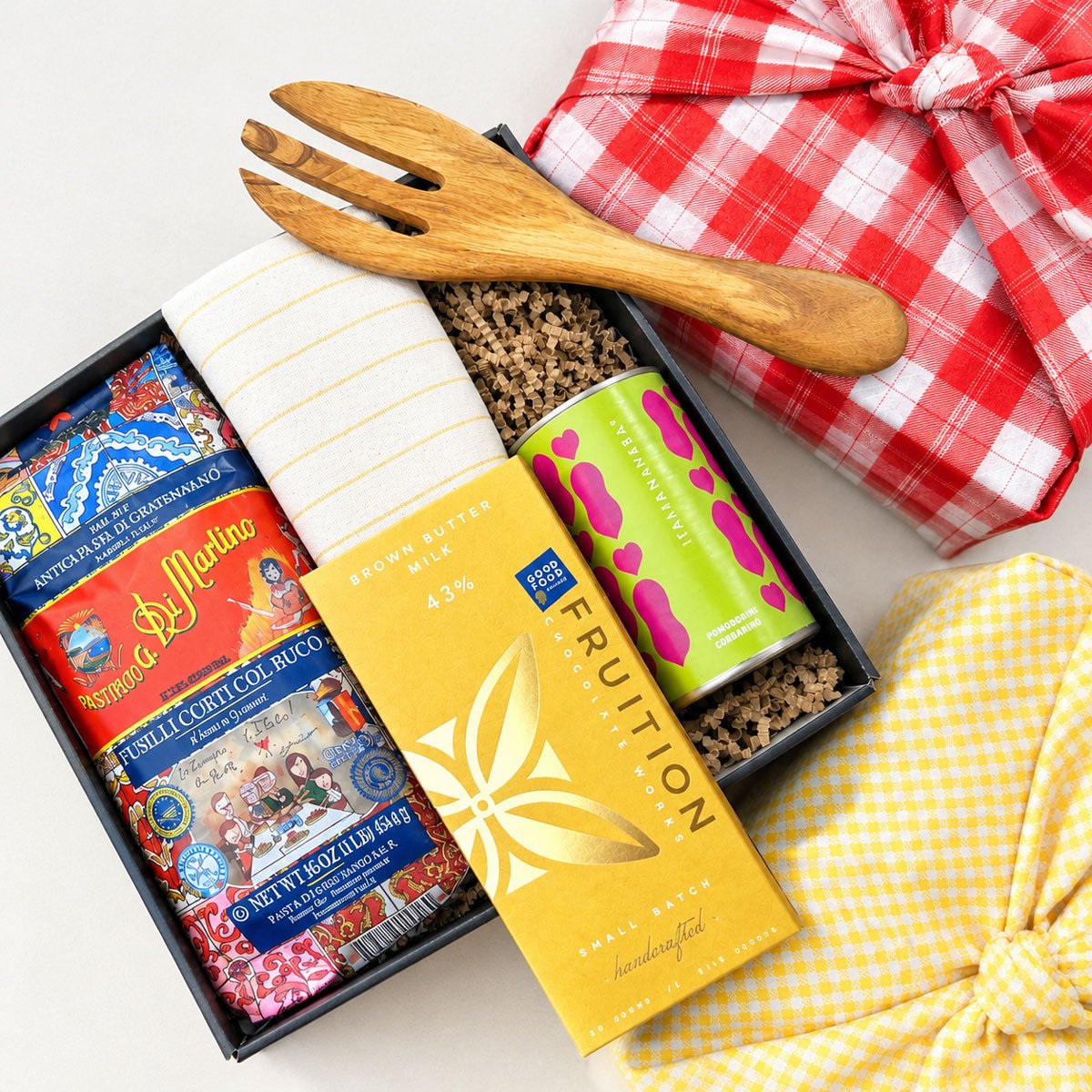Kadoo gift set with a wooden fork, pasta, sauce, chocolate, and tea towel with furoshiki wrapping.