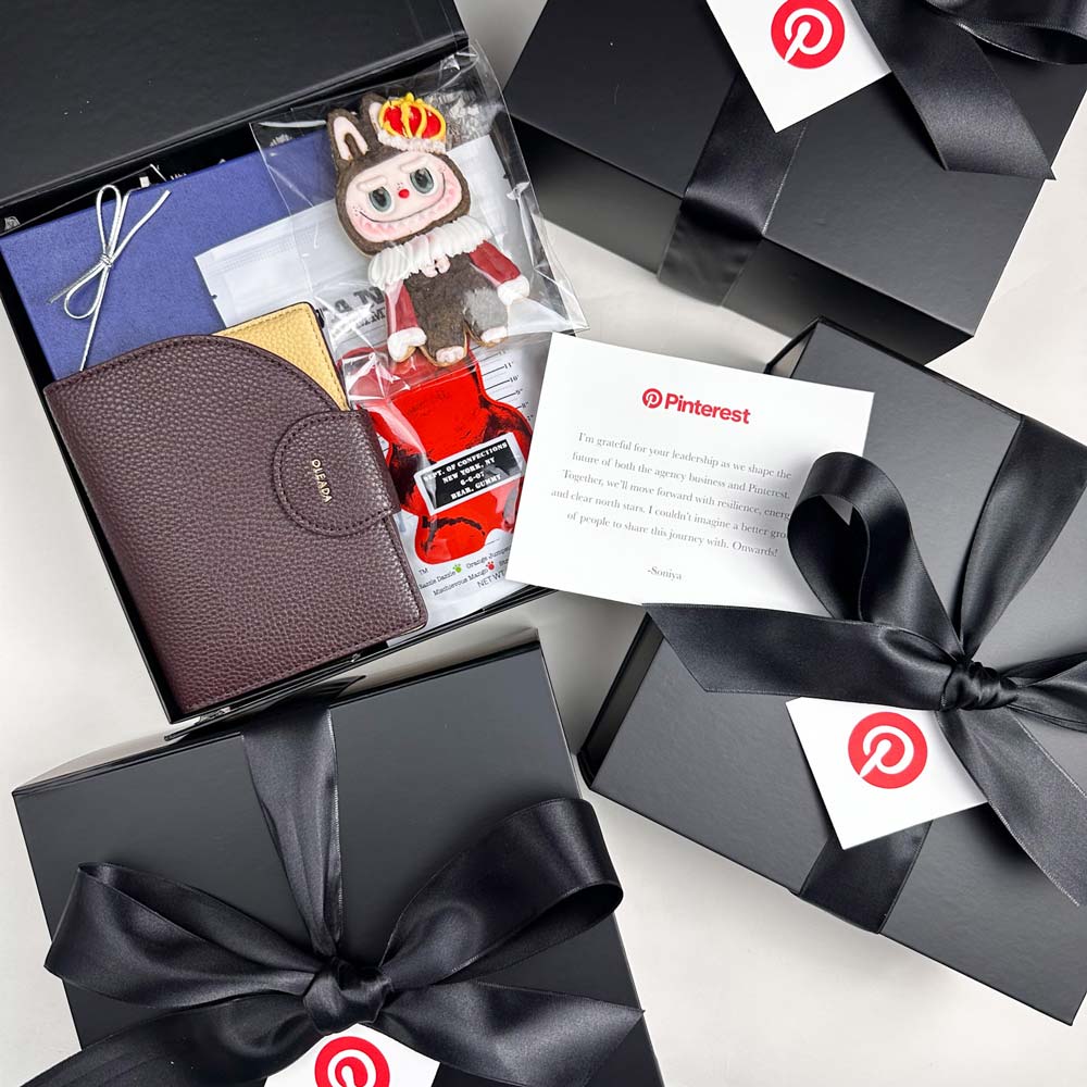 Gift box with a wallet, plush toy, and stationery items, featuring Pinterest logos.