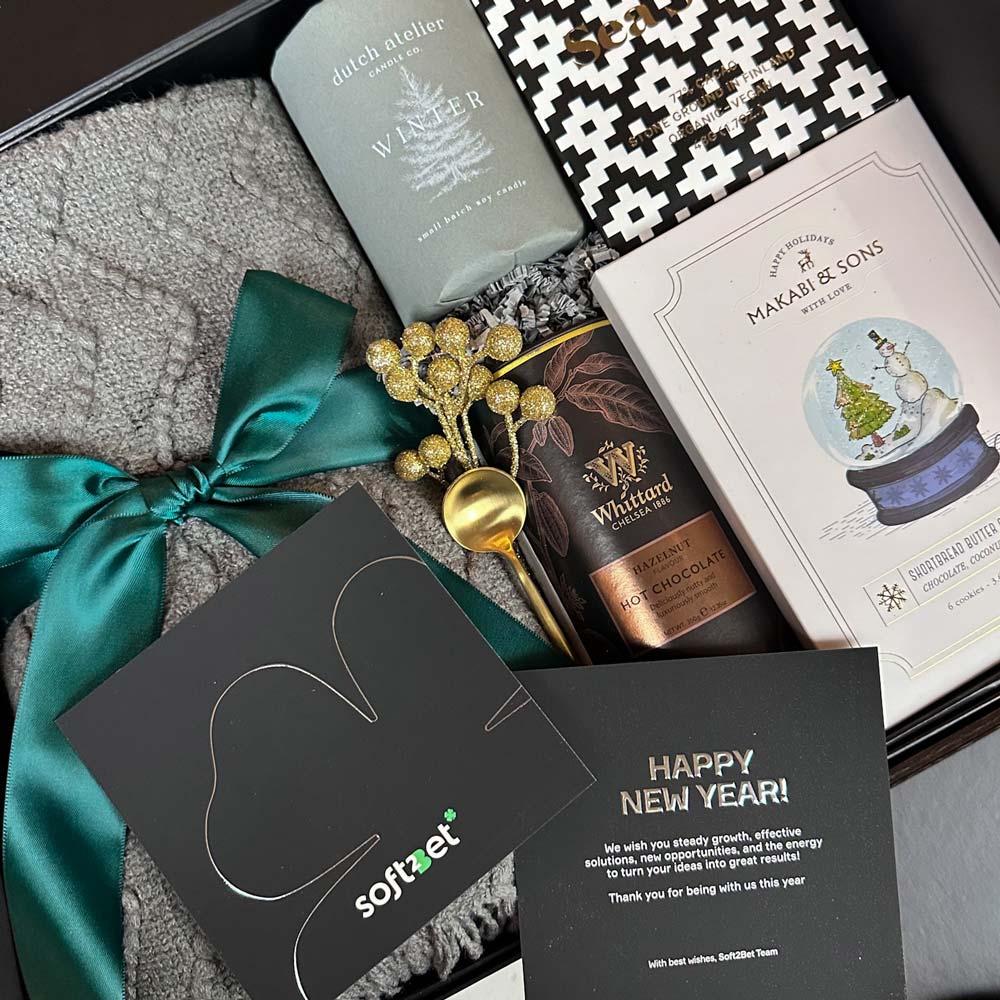 Gifting box with a bottle of hot chocolate, a book, a card, and decorative elements.