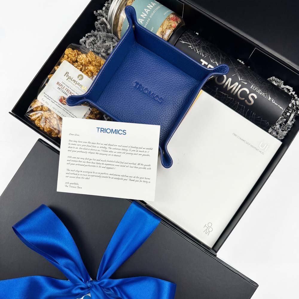 Gift box with a blue tray, bow, and Triomics branding