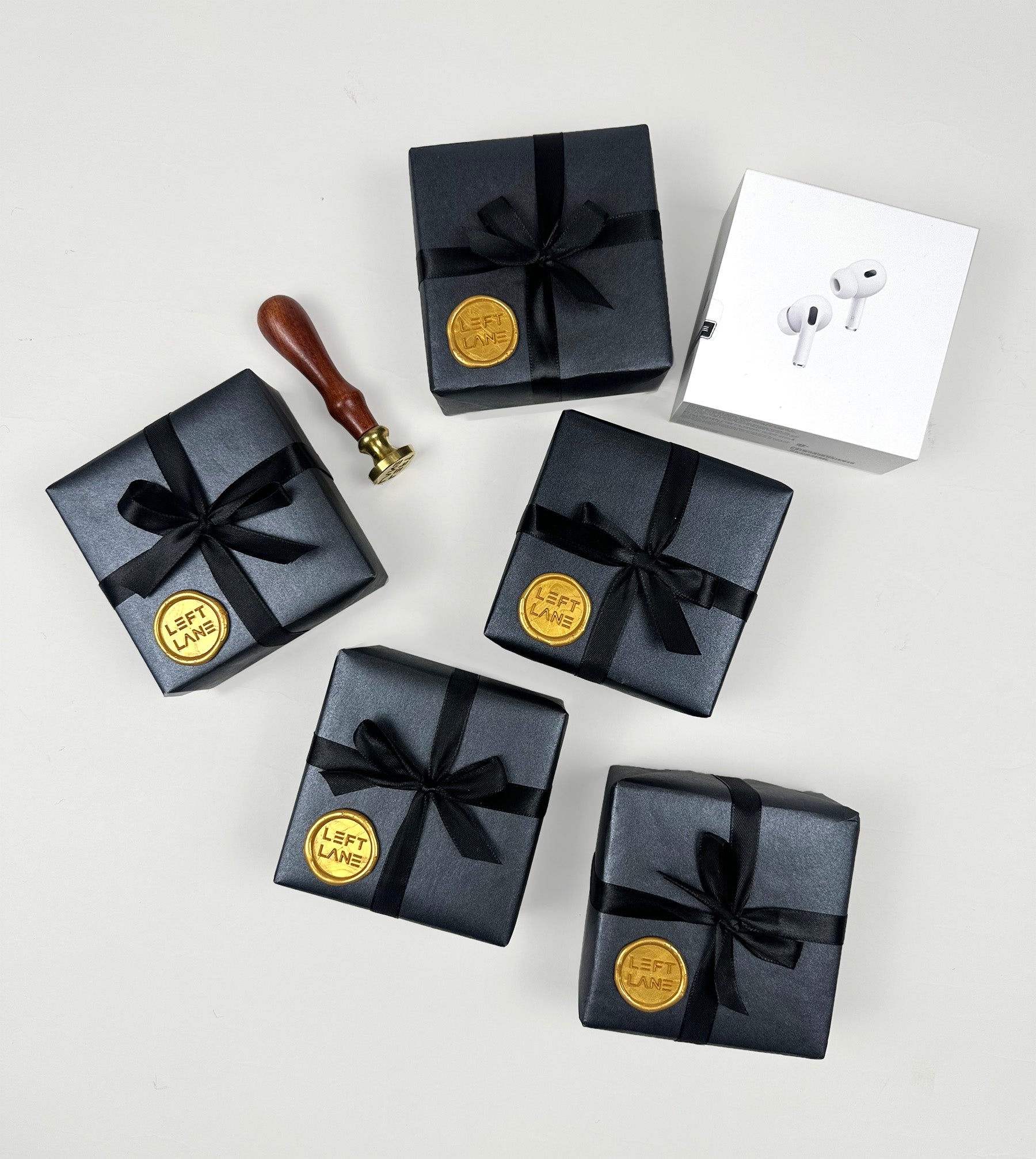 Left Lane black gift box wrapped in black paper and black ribbon. Gold Wax seal. Apple Airpod Pro gift.