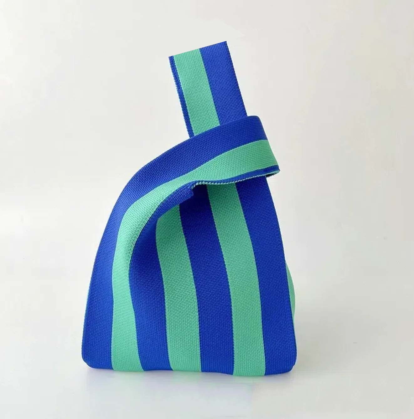 A small fabric handbag with bold vertical blue and mint green stripes, featuring a matching fabric loop handle, set against a plain light background.