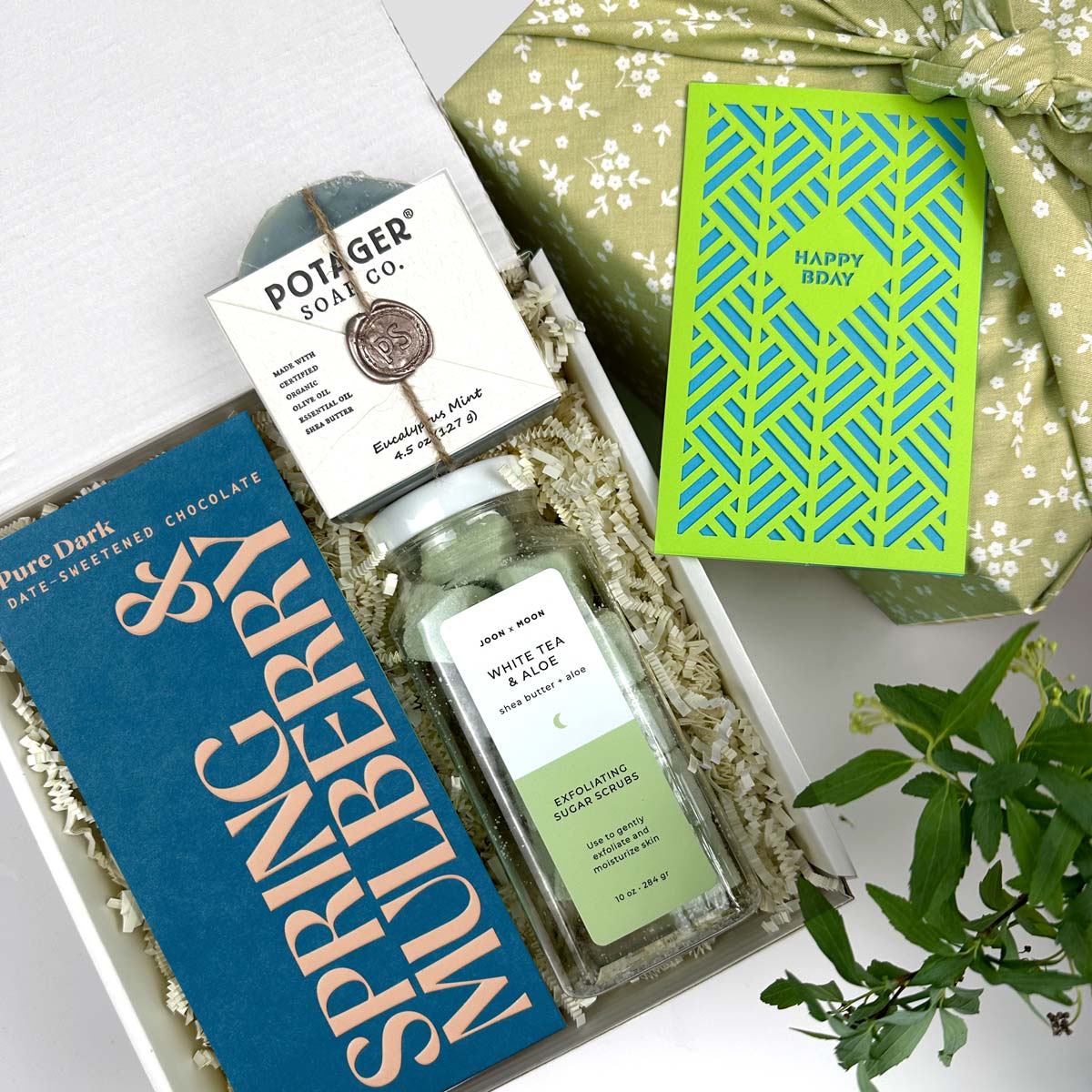 Kadoo gift set with chocolate, soap, perfume, and a card on a white background