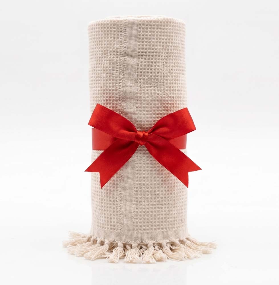 ivory color blanket rolled up with red ribbon against white background