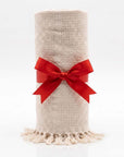 ivory color blanket rolled up with red ribbon against white background