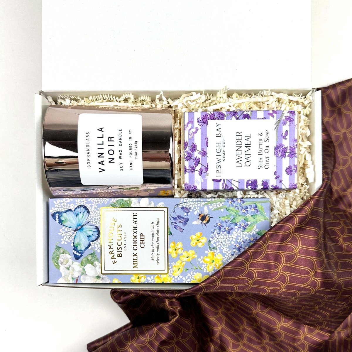 kadoo curated gift with milk chocolate chip in purple packaging, vanilla noir candle in glass pink container, lavender oatmeal bar soap, and furoshiki fabric wrap