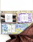 kadoo curated gift with milk chocolate chip in purple packaging, vanilla noir candle in glass pink container, lavender oatmeal bar soap, and furoshiki fabric wrap