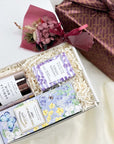 kadoo curated gift with milk chocolate chip in purple packaging, vanilla noir candle in glass pink container, lavender oatmeal bar soap, dried-flower and furoshiki fabric wrap