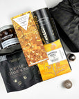 kadoo celebration holiday curated gift box with black furoshiki wrap. Inside gifts: pop the champagne popcorn, champagne chocolate bar, caramel latte biscuits, shortbread, chocolate raspberry cremes and more