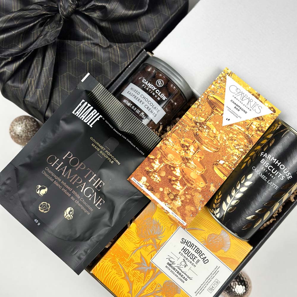 kadoo celebration furoshiki holiday gift box in black and yellow gold color. Gifts inside chocolate, popcorn, biscuits, shortbread and more