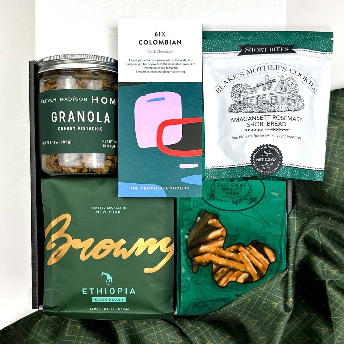 kadoo curated holiday gift box with eleven madison home granola, browny gourmet coffee, pretzel, rosemary shortbread, dark chocolate, green fabric wrapand more