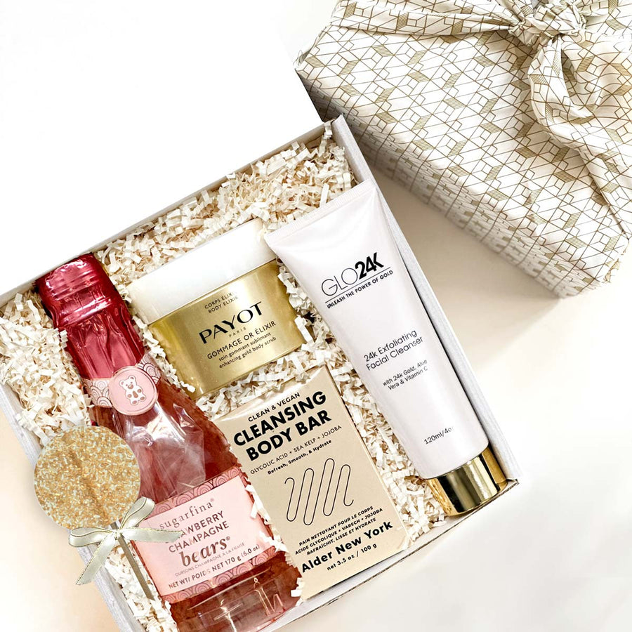 kadoo glowing gold luxurious spa gift box for her wrapped in furoshiki fabric. Include body scrub, 24K facial cleanser, sugarfina gummy, body elixir, lollipop & more.