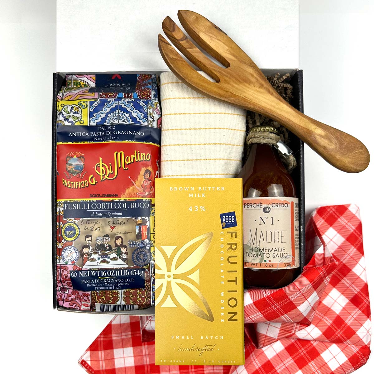 kadoo pasta night curated gift box with dry pasta, chocolate bar, homemade tomato sauce, yellow stripes kitchen towel, olive wooden fork utensil, red fabric wrap, and more