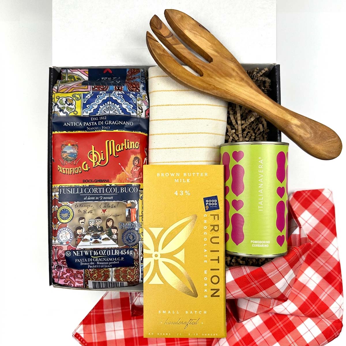 Kadoo Gift set with pasta, chocolate, and a wooden fork on a red checkered furoshiki cloth.