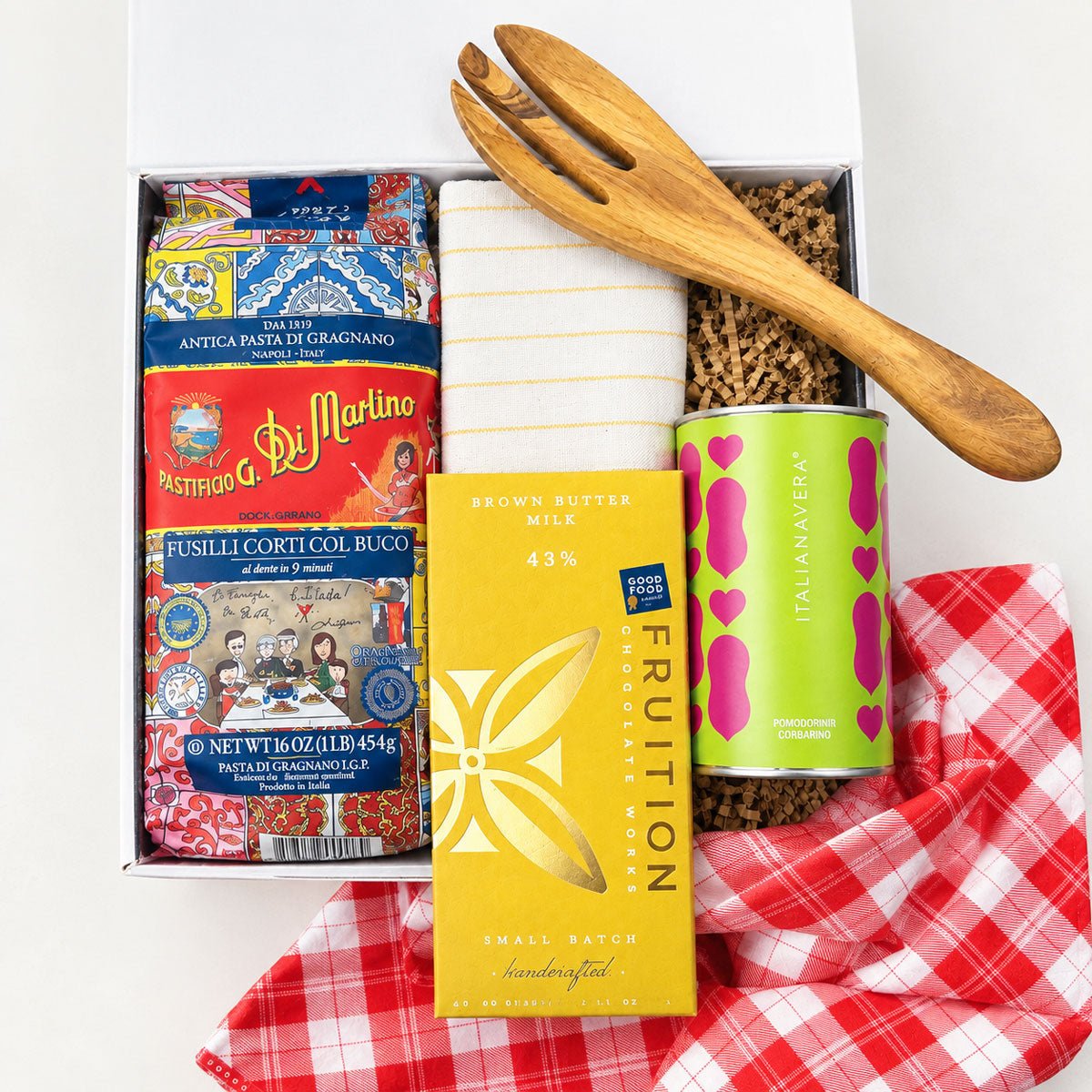 Kadoo Gift set with pasta, chocolate, and a wooden fork on a red checkered furoshiki cloth.