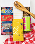Kadoo Gift set with pasta, chocolate, and a wooden fork on a red checkered furoshiki cloth.