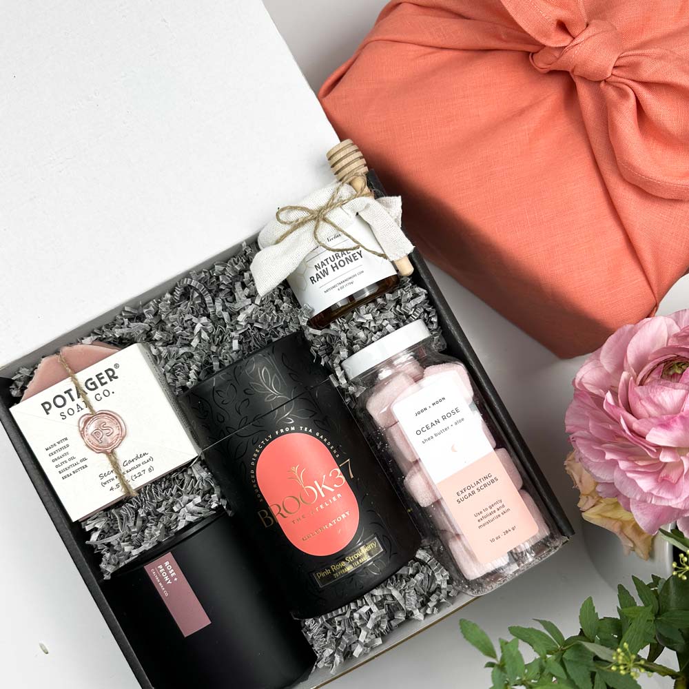 kadoo rose garden spa gift box wrapped in coral fabric linen. Gift inside box: soap, candle, tea, honey, sugar scrub and more.