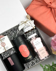 kadoo rose garden spa gift box wrapped in coral fabric linen. Gift inside box: soap, candle, tea, honey, sugar scrub and more.