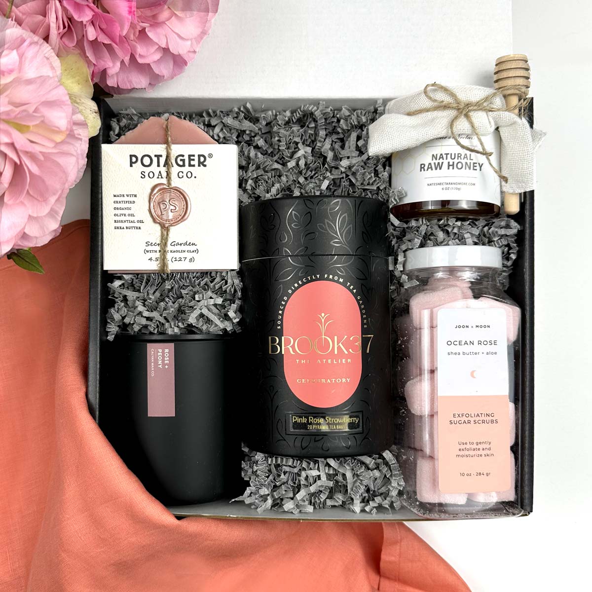 kadoo rose garden gift box with soap, candle, pink rose strawberry tea, sugar scrub, honey, coral linen, gray crinkle paper and more.