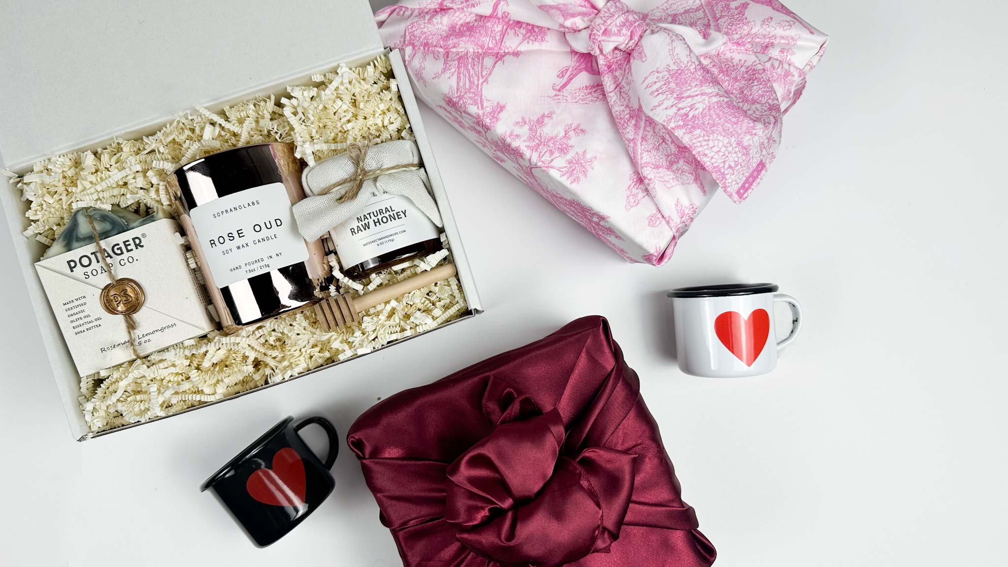 kadoo valentine gifts for her. gift box with candle, honey, soap, heart mugs and more. Wrapped in pink and red fabric.