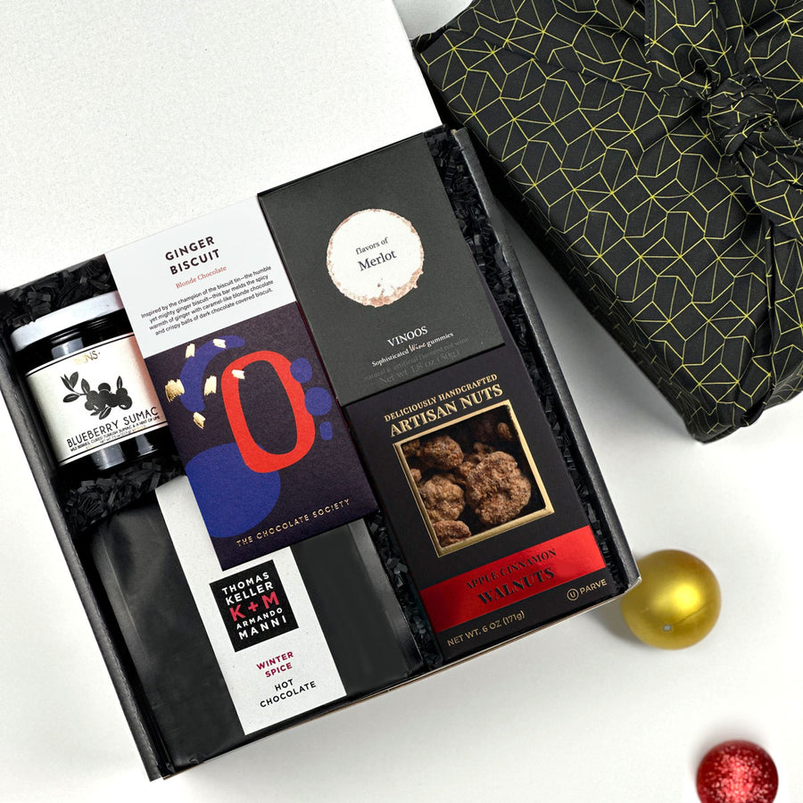 kadoo winter spice holiday curated gift box. Packed with winter treats: hot chocolate, chocolate bar, merlot wine gums, jam, artisan nuts and more. wrapped in reusable furoshiki fabric.