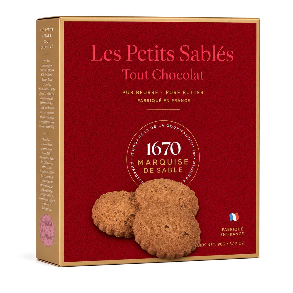 A box of Les Petits Sablés Tout Chocolat cookies, featuring a deep red front with the brand name in gold and pink, and three chocolate-scented cookies pictured on the front. The box has a gold-colored side panel and is set against a plain white background.