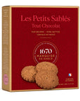 A box of Les Petits Sablés Tout Chocolat cookies, featuring a deep red front with the brand name in gold and pink, and three chocolate-scented cookies pictured on the front. The box has a gold-colored side panel and is set against a plain white background.
