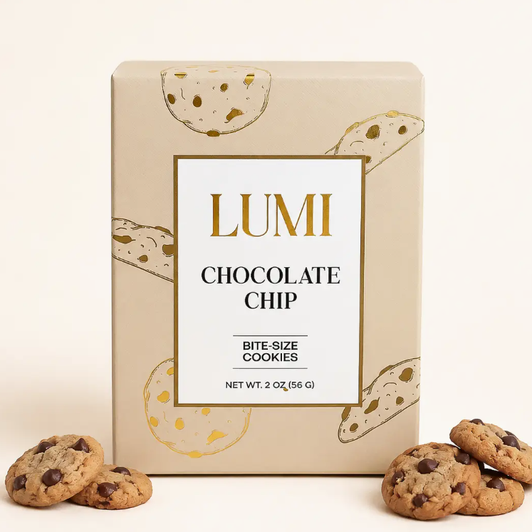 A box of Lumi Chocolate Chip bite-size cookies on a white background, with several chocolate chip cookies placed in front of the box.