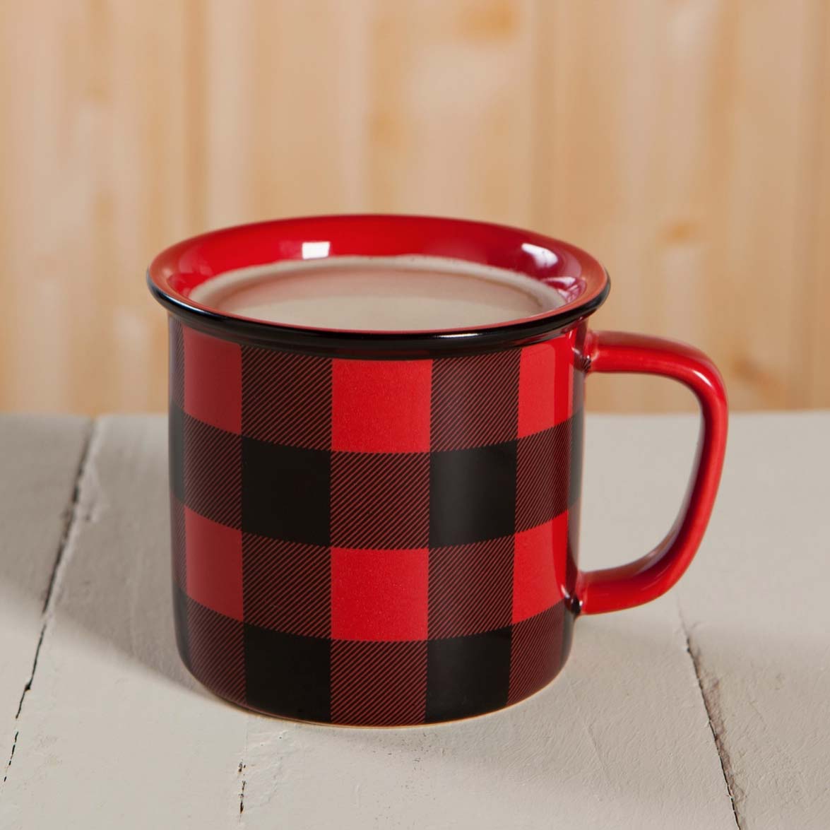 Red and black checkered mug with a handle on a wooden surface