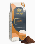 A package of Whittard of Chelsea 1886 Salted Caramel Flavoured Coffee, shown standing upright with a small pile of ground coffee in front on a white background.
