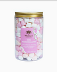 A clear plastic jar filled topped with a gold metal lid with pink and white mini marshmallows, featuring a pink label for Whittard of Chelsea 1954.
