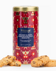 A cylindrical tin of Whittard Orange & Dark Chocolate Chip Biscuits on a white background, with several golden-brown chocolate chip cookies placed in front of the tin.