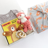 KADOO baby gift box in Furoshiki Fox wrap. Inside organic onesie, baby book, Fox stuffed animals, & Silicon + wooden rattle.