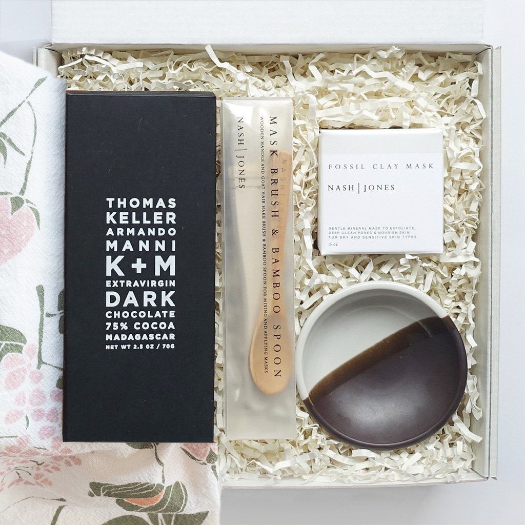 KADOO Radiant Beauty gift box. Contains dark chocolate bar, clay mask set with mixing bowl, wooden spoon and a soft goat hair brush. Wrapped in flour sack tea towel in floral pattern.