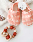 baby girl wooden teething rattle and pink baby girl shoes.