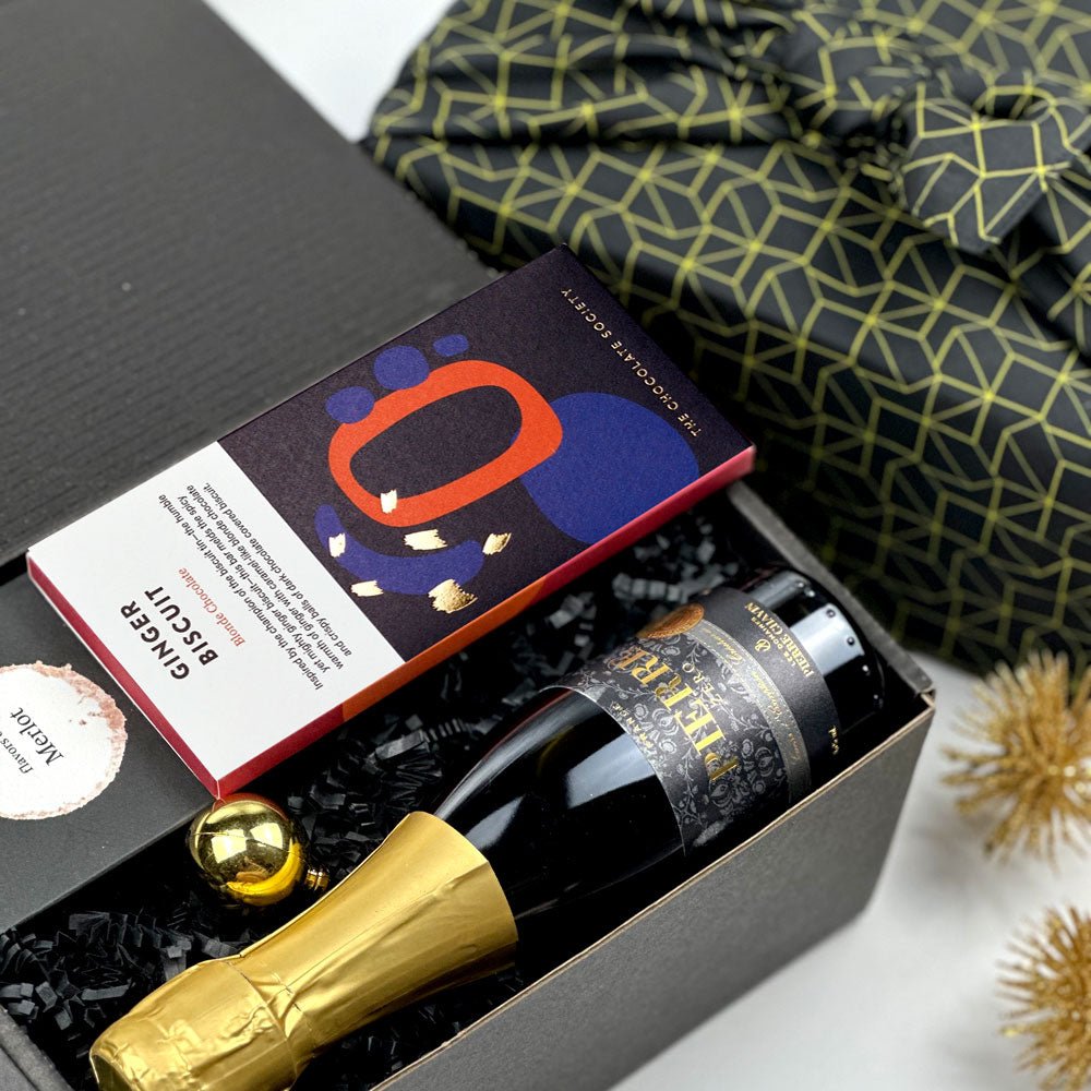 kadoo celebration holiday curated gift box wrapped in reusable Furoshiki fabric. Filled with pierre zero-alcohol sparkling wine, ginger biscuit chocolate, wine gummies.